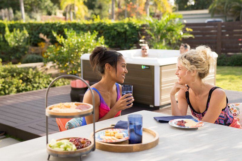 A couple of friends having lunch by a Limelight Flair hot tub